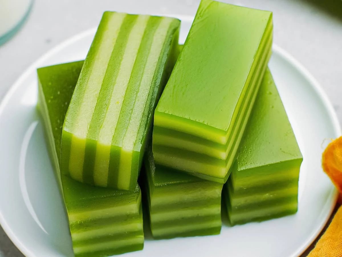 A perfectly sliced banh da lon revealing multiple colorful layers - green pandan, white coconut, and yellow mung bean